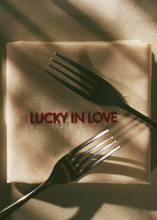 Салфетка с надписью Lucky in Love и две вилки в тёплом свете — детали сервировки
